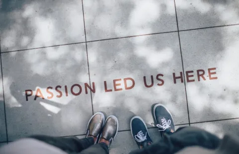 Two people's feet in front of the message, "Passion Led Us Here"